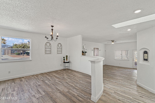 interior space with baseboards, light wood-type flooring, recessed lighting, a skylight, and a textured ceiling