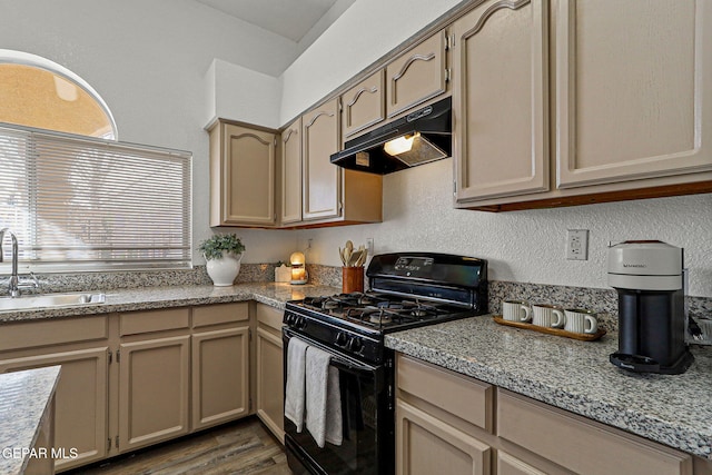 kitchen featuring dark wood-type flooring, under cabinet range hood, black gas range, a textured wall, and a sink