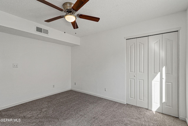 unfurnished bedroom featuring visible vents, a textured ceiling, a closet, carpet, and ceiling fan