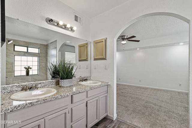 full bath with visible vents, a textured ceiling, ceiling fan, and a sink