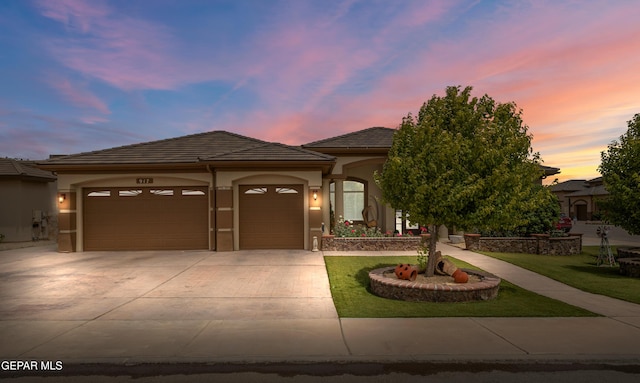 view of front of property with an attached garage, stucco siding, driveway, a front lawn, and a tile roof