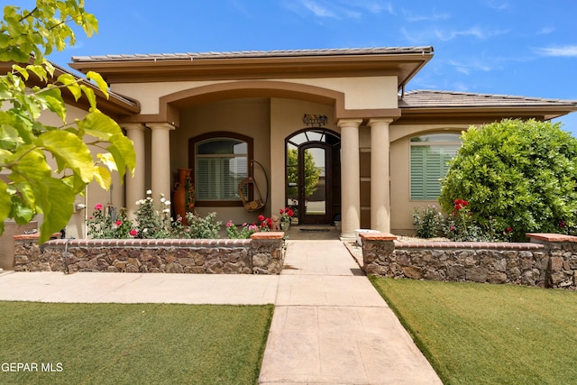 doorway to property with a yard and stucco siding