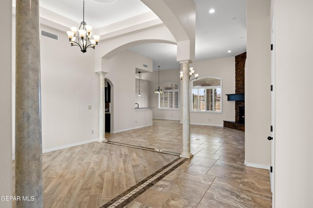 unfurnished room with a chandelier, arched walkways, recessed lighting, baseboards, and a fireplace