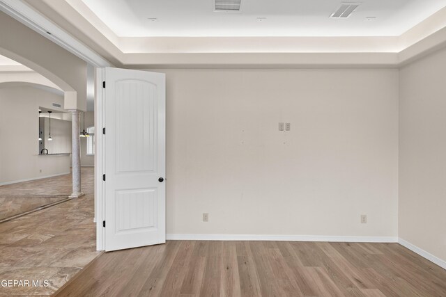 unfurnished room with arched walkways, wood finished floors, and baseboards