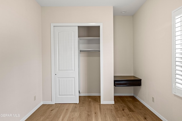 unfurnished bedroom featuring wood finished floors, a closet, and baseboards