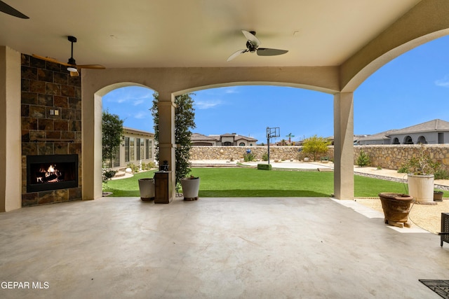 view of patio featuring an outdoor stone fireplace and a ceiling fan