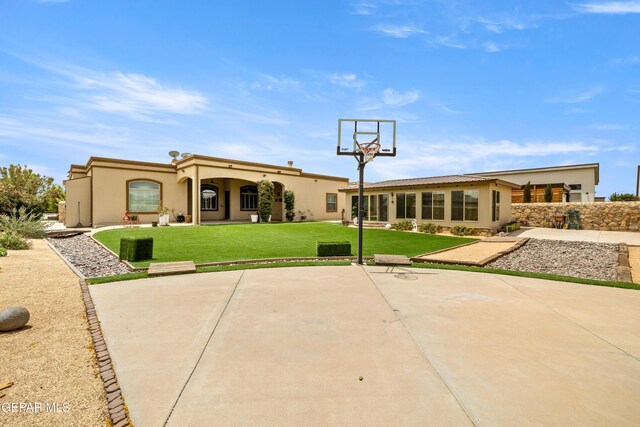 back of house with stucco siding, a patio, and a lawn