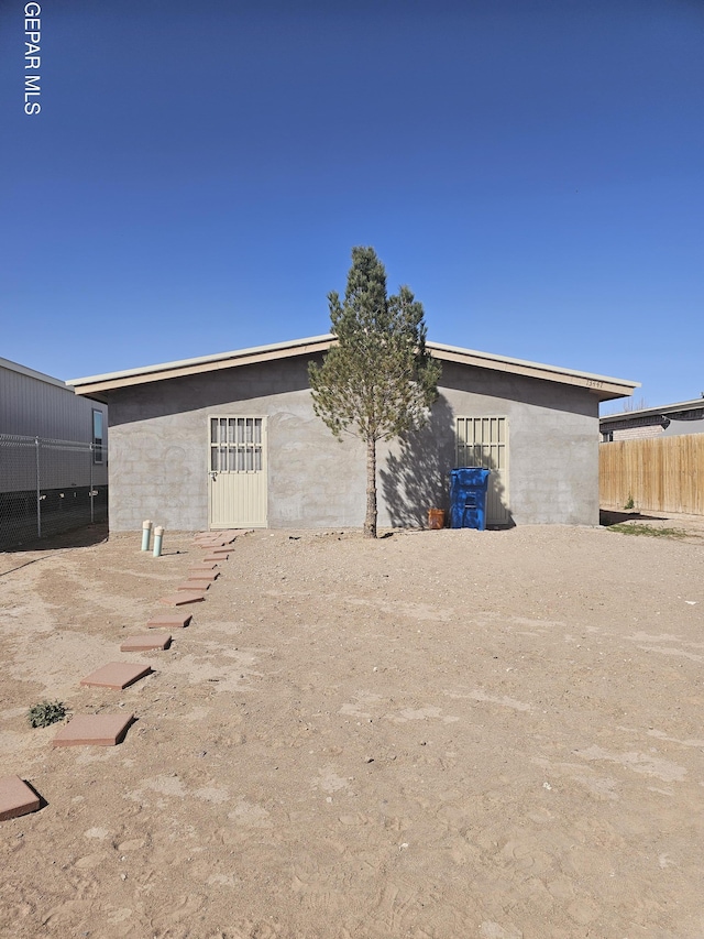 exterior space featuring stucco siding and fence