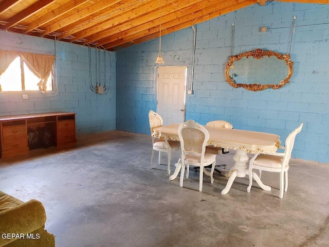 dining space with vaulted ceiling and unfinished concrete floors