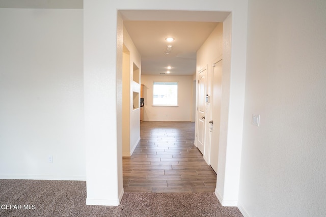 corridor featuring baseboards and carpet flooring