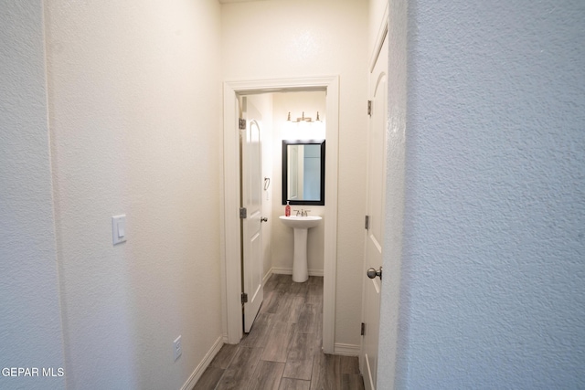 hallway with dark wood-style floors, baseboards, and a textured wall