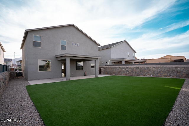 back of house featuring a patio area, stucco siding, a lawn, and a fenced backyard