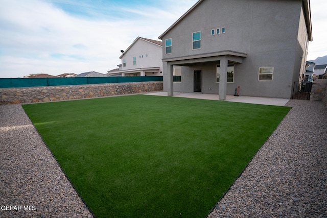 rear view of house with a yard, a patio, a fenced backyard, and stucco siding