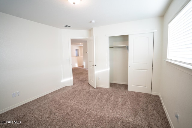 unfurnished bedroom featuring a closet, visible vents, baseboards, and carpet