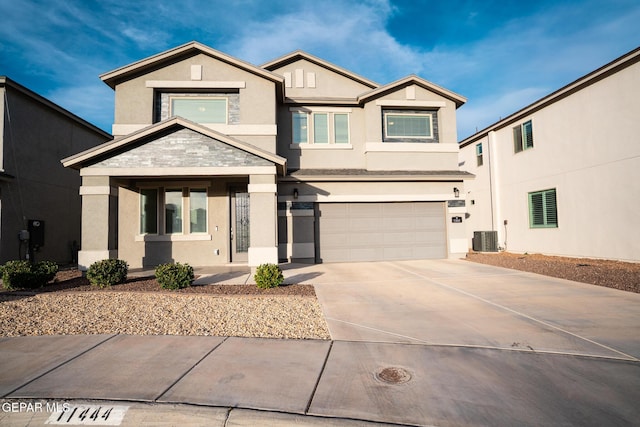 view of front of property with stucco siding, driveway, an attached garage, and central AC
