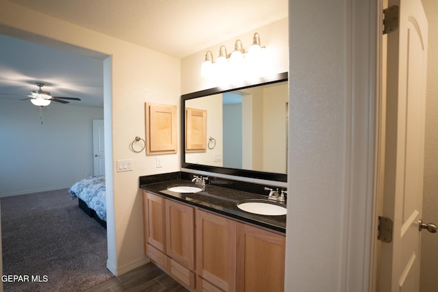 ensuite bathroom with a sink, baseboards, ceiling fan, and double vanity