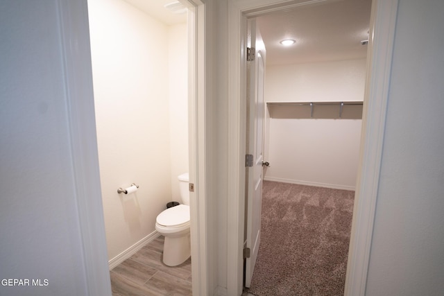 bathroom with toilet, wood finished floors, and baseboards
