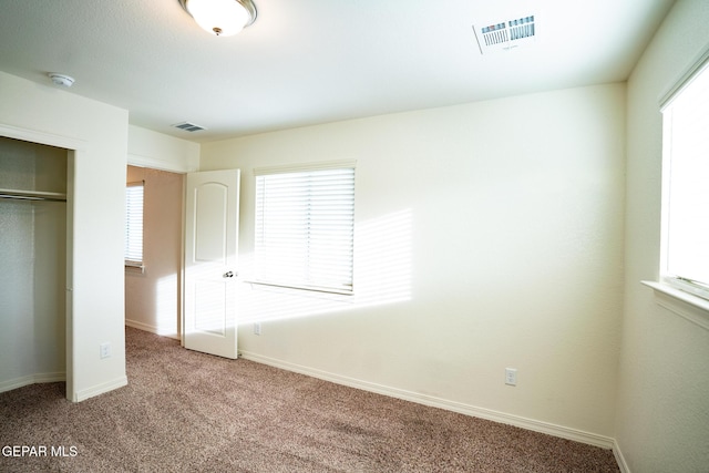 unfurnished bedroom featuring a closet, visible vents, baseboards, and carpet floors