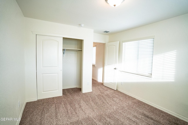 unfurnished bedroom featuring visible vents, baseboards, a closet, and carpet flooring