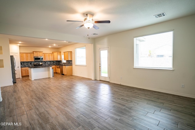 kitchen featuring a ceiling fan, visible vents, open floor plan, dark countertops, and tasteful backsplash