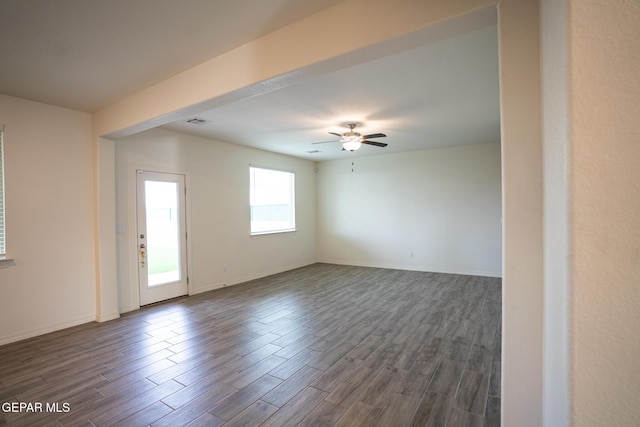 empty room featuring baseboards, visible vents, dark wood-style flooring, and ceiling fan