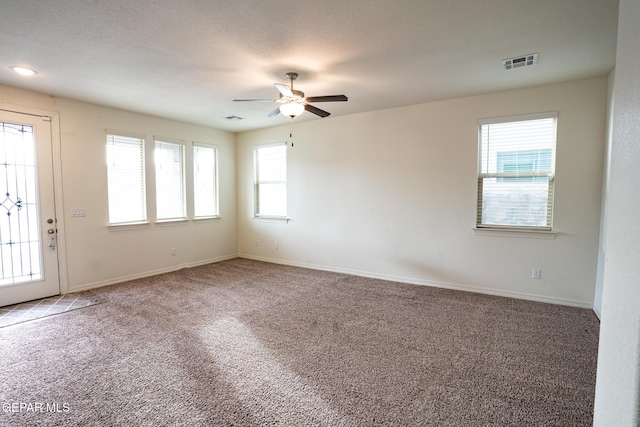 empty room with visible vents, baseboards, carpet, and a ceiling fan