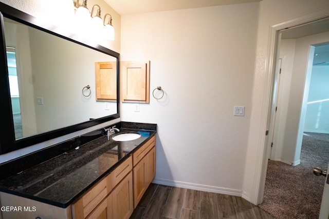 bathroom with baseboards, wood finished floors, and vanity