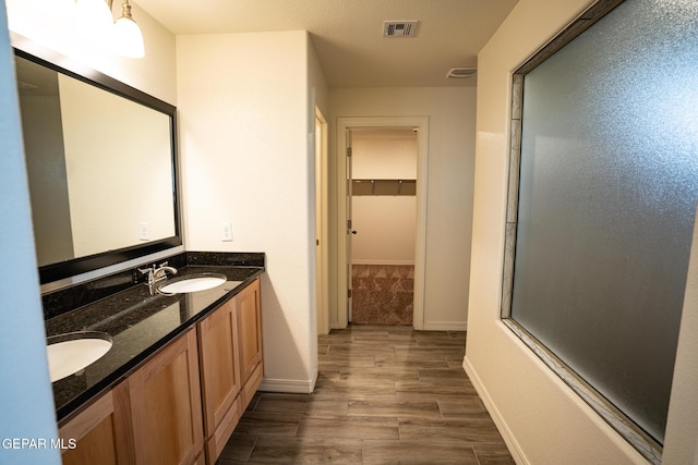 full bath featuring wood tiled floor, double vanity, visible vents, and a sink