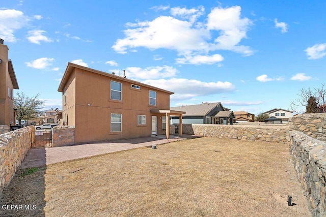 rear view of property with a gate, fence, stucco siding, a patio area, and a residential view