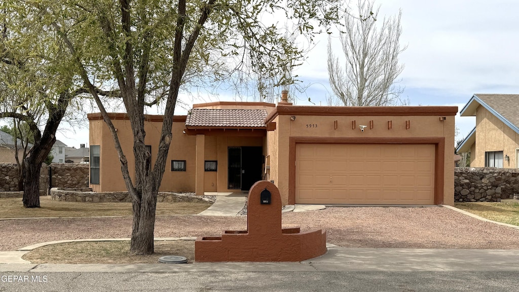 5913 Oleaster Dr, El Paso, TX 79932 - adobe home with an attached garage, driveway, a tile roof, and stucco siding