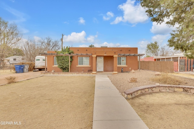 pueblo-style house featuring fence and stucco siding