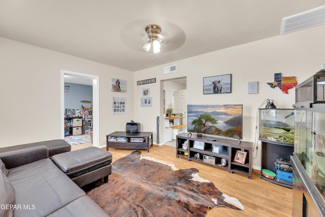 living area with visible vents, baseboards, ceiling fan, and wood finished floors