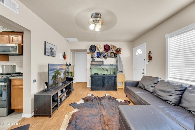 living room with light wood-style flooring, visible vents, and ceiling fan