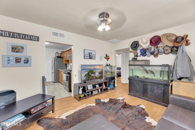 living area with visible vents, light wood-type flooring, and ceiling fan