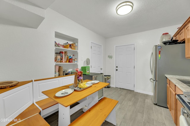 dining space with light wood-style flooring and a textured ceiling