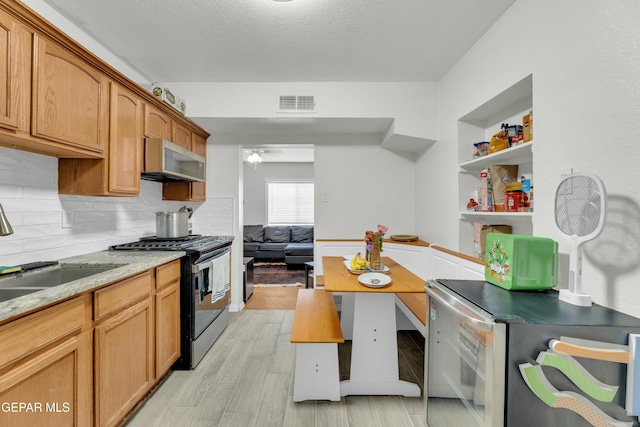 kitchen featuring stainless steel microwave, visible vents, light wood-style floors, gas stove, and a sink