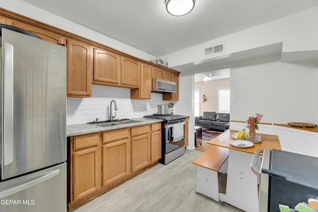 kitchen with light stone countertops, visible vents, a sink, decorative backsplash, and stainless steel appliances