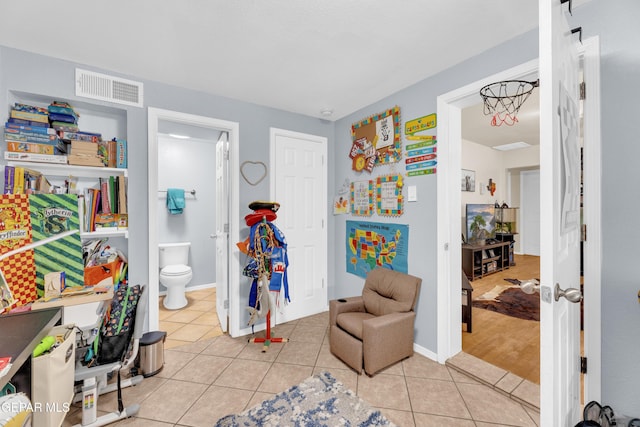 interior space featuring light tile patterned floors, baseboards, visible vents, and ensuite bathroom