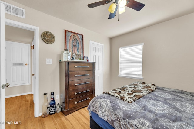 bedroom featuring a ceiling fan, light wood-style flooring, baseboards, and visible vents