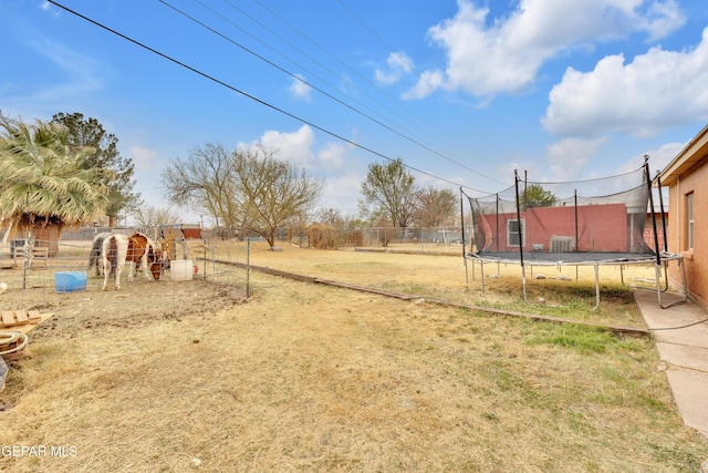 view of yard with a trampoline and fence