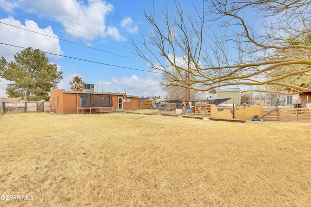 view of yard featuring an outbuilding, a trampoline, and fence