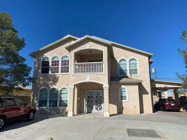 view of front of home with stucco siding, a balcony, and concrete driveway