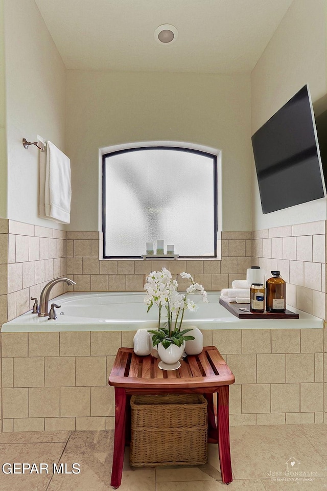 bathroom with a garden tub and tile patterned flooring