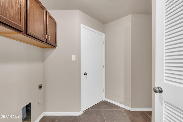 clothes washing area with cabinet space, hookup for an electric dryer, baseboards, and dark tile patterned flooring