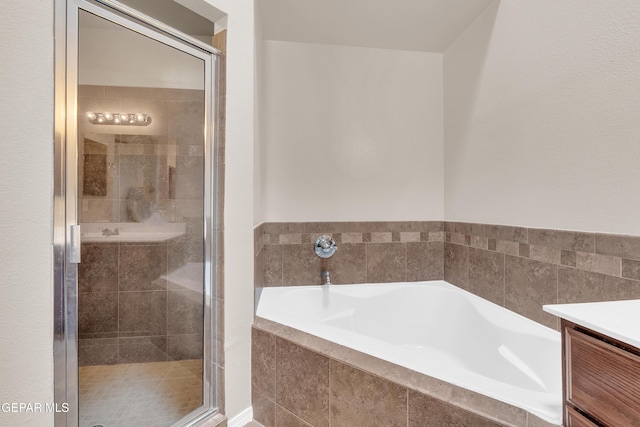 full bath with vanity, a garden tub, and a stall shower