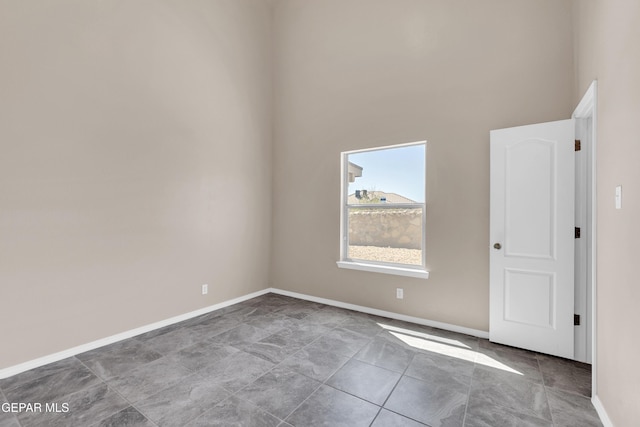 empty room with a high ceiling and baseboards