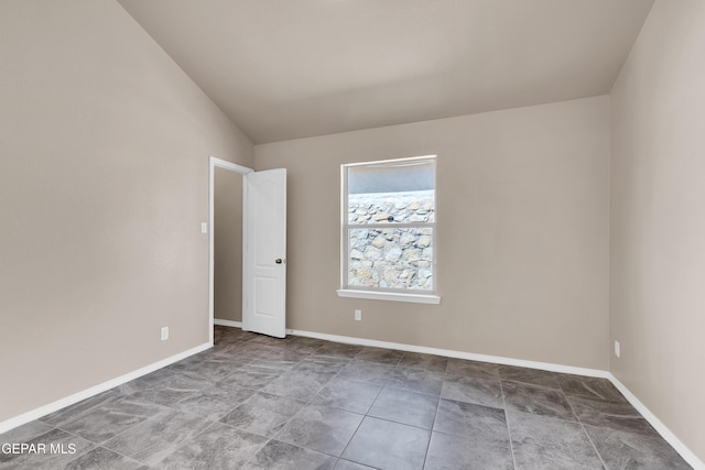 unfurnished room featuring lofted ceiling and baseboards
