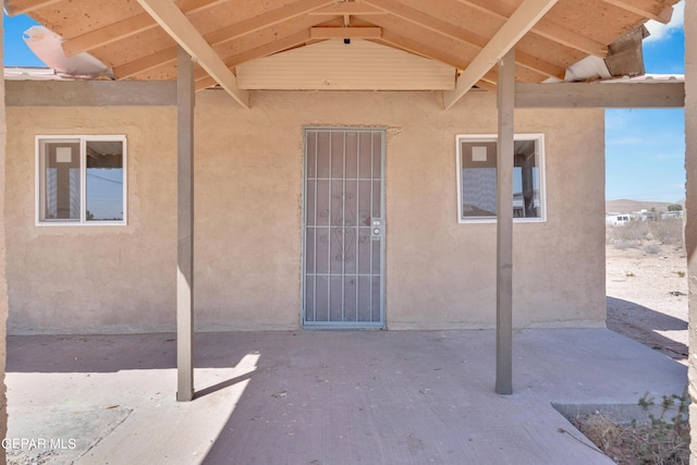 entrance to property with stucco siding and a patio