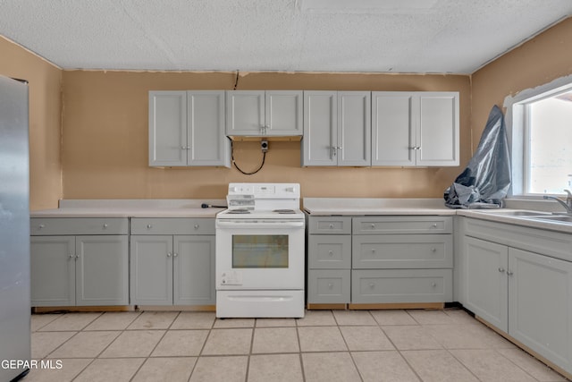 kitchen featuring light countertops, a sink, gray cabinetry, and electric stove