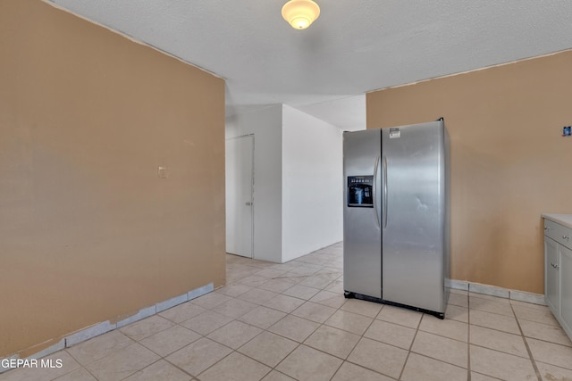 kitchen featuring stainless steel fridge with ice dispenser, baseboards, and light tile patterned flooring